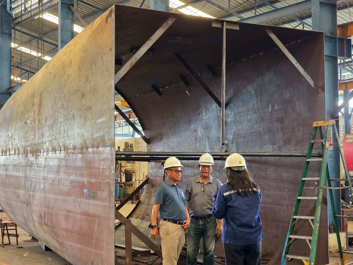 Phenovate engineers reviewing a large fabricated steel shell on the workshop floor